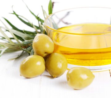 A bottle of extra-virgin olive oil and fresh olives.