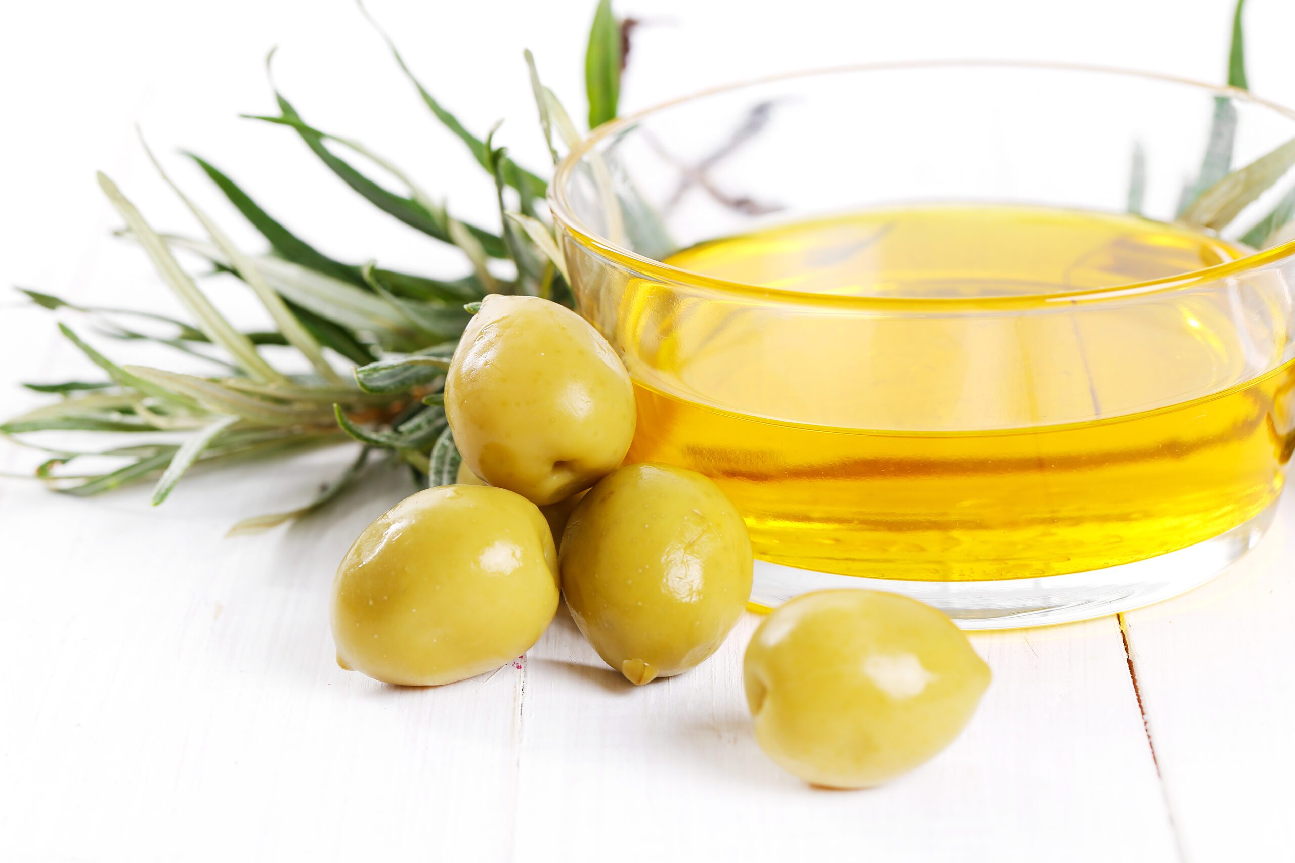 A bottle of extra-virgin olive oil and fresh olives.